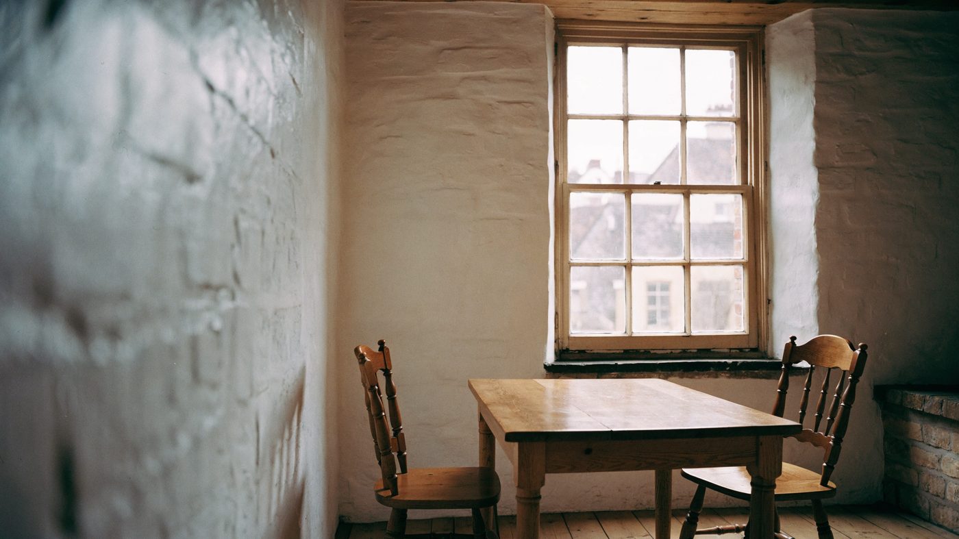 A side room in a period market-town hall, plain oak table and wooden chairs beneath a tall multi-pane window