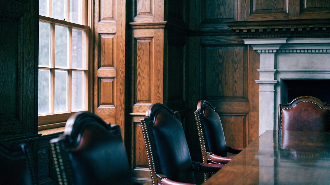 A traditional wood-panelled City boardroom, long polished table and leather-backed chairs beside a tall sash window