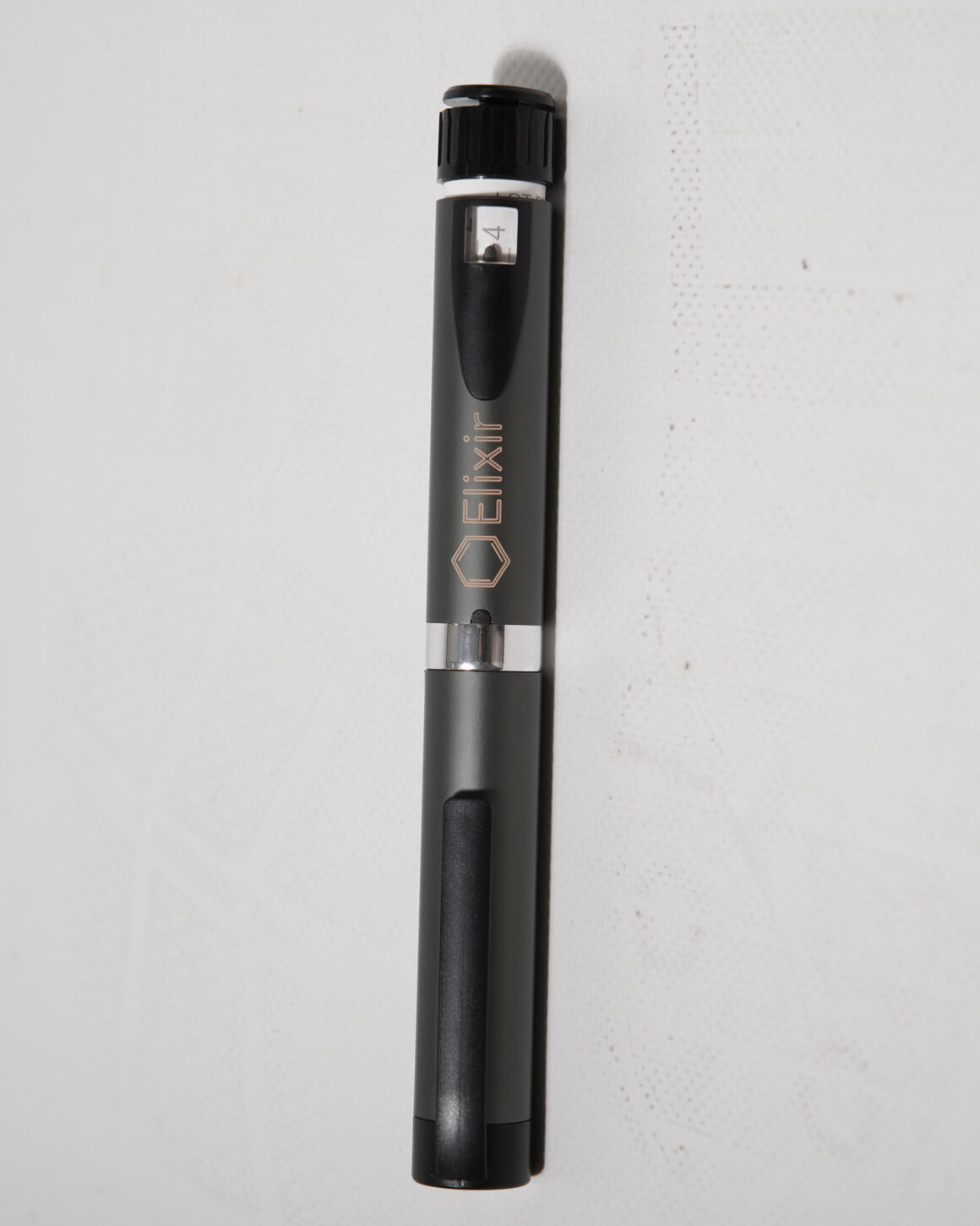 The Elixir Pen — a matte black and grey reusable injector pen with the Elixir mark on the barrel